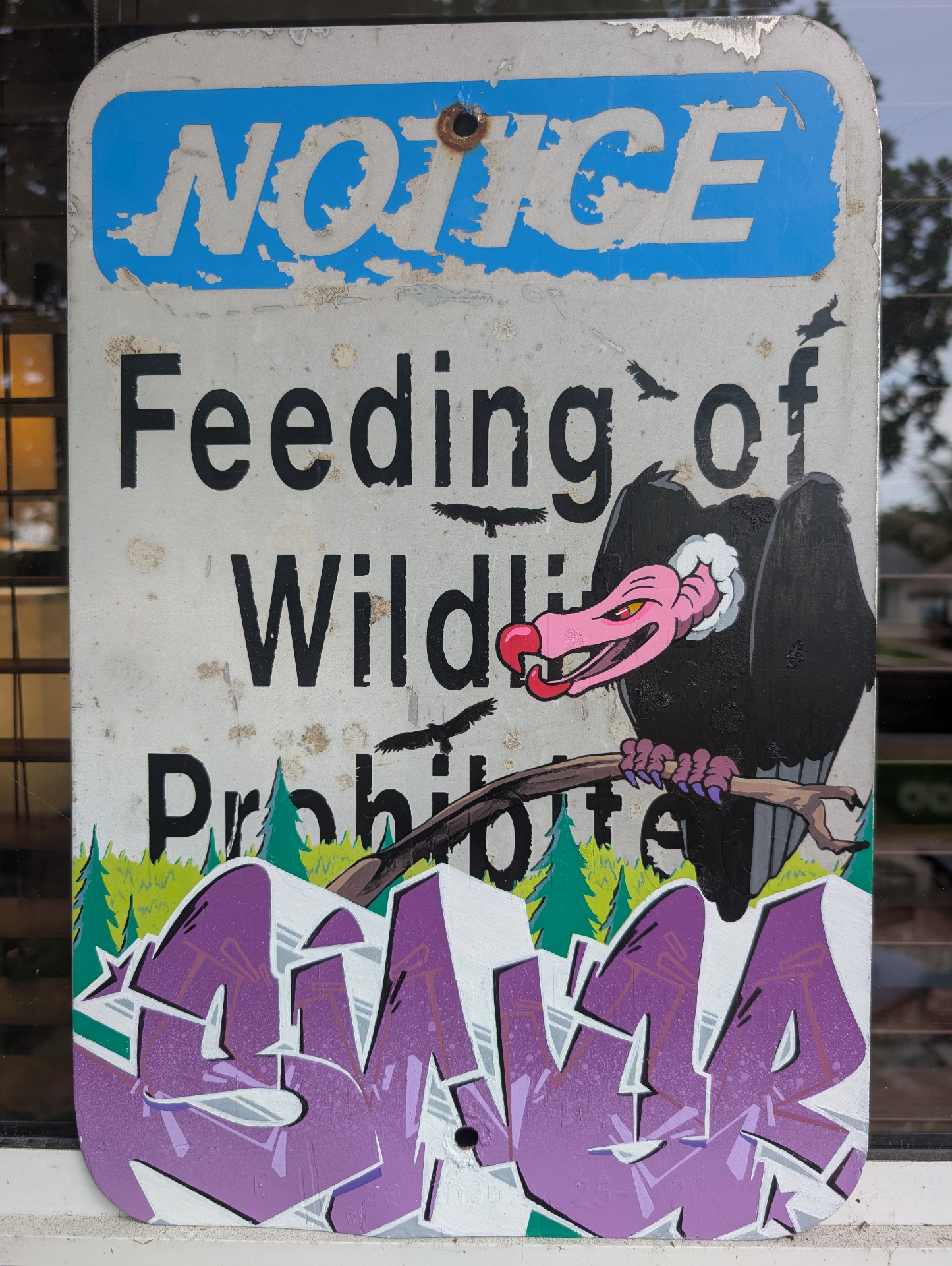 Weathered wildlife notice sign painted with purple SINER letters and vulture character