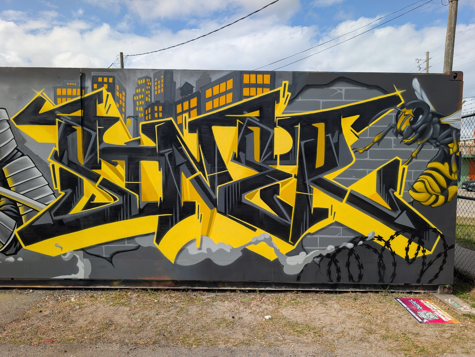 Yellow and black SINER wildstyle mural with city skyline and hornet character